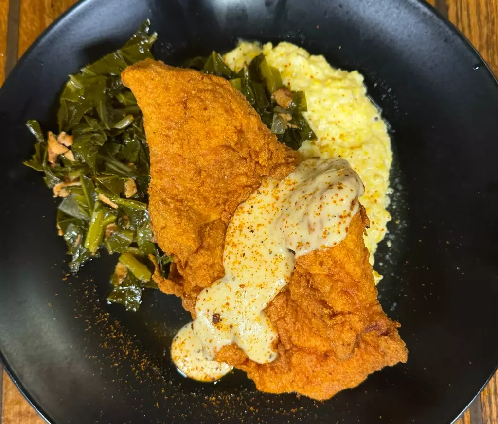 Chicken-fried, bone-in porkchop with bacon-braised greens, grits, and miso white gravy