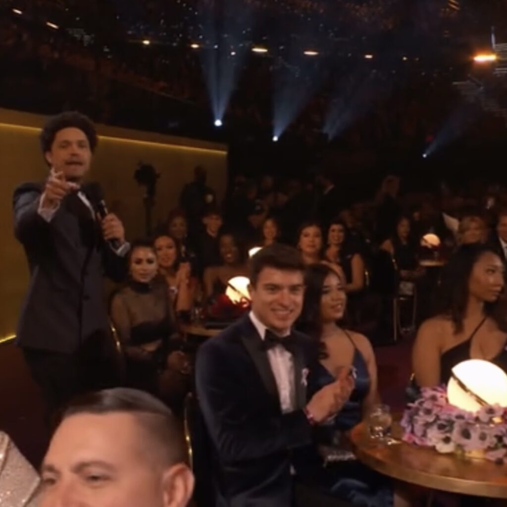 Headshot of Connor Ripple sitting and posing on a director's chair, with a big smile.