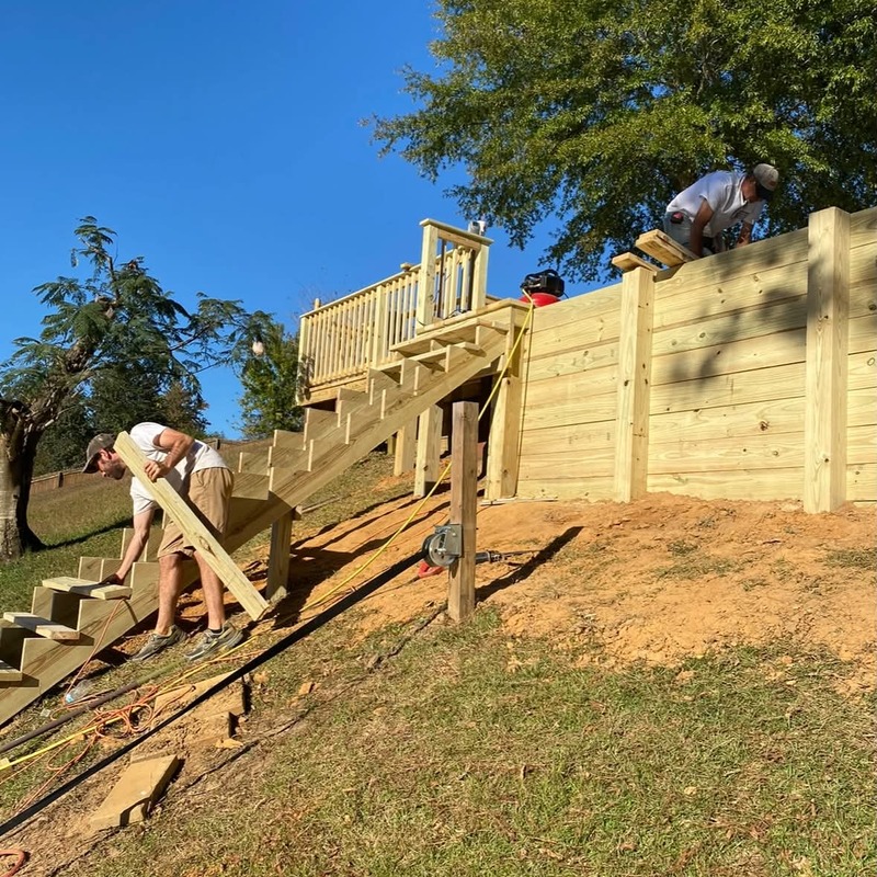 Elevated wooden deck and staircase under construction on a sloped yard