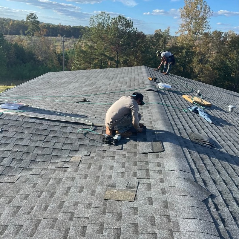 Roofing contractors installing asphalt shingles on a residential roof