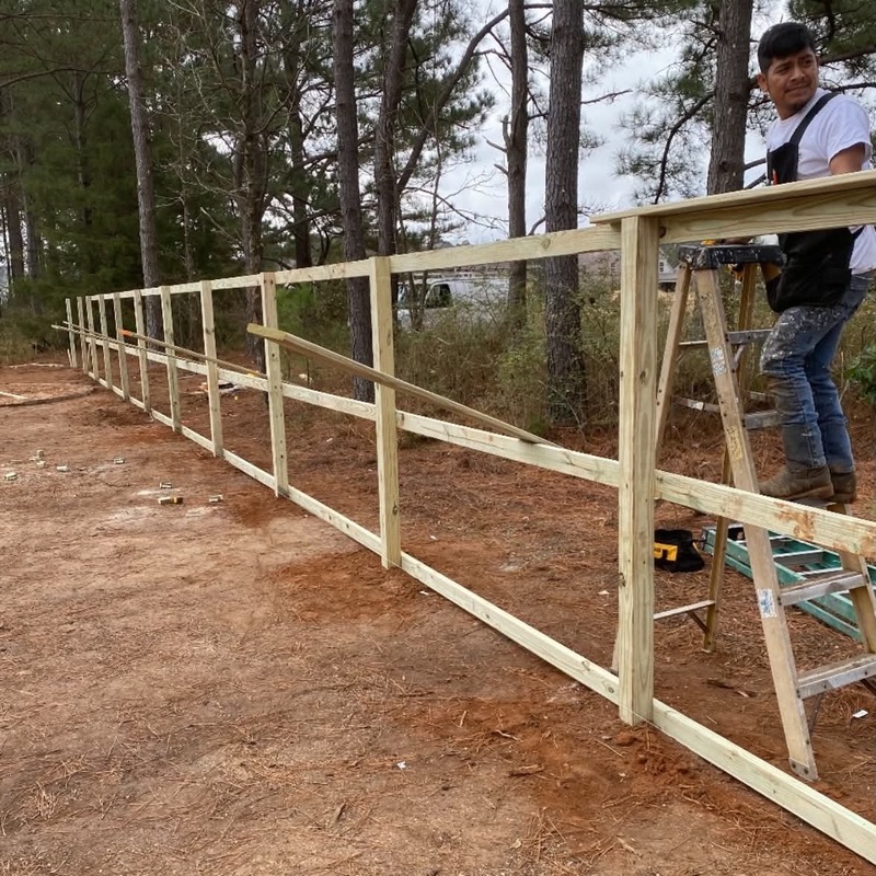 Contractor building a custom wooden fence frame along a residential property
